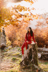 beautiful woman relax in autumn forest. Portrait of long hair woman in warm outfit walk in forest at sunset. 