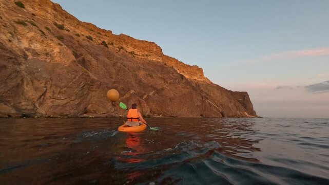 Kayak ocean cliff paddler exploring rugged coastline at golden hour adventure travel