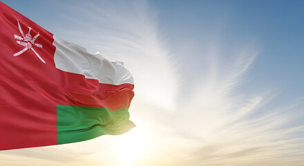 Oman Flag Waving Proudly Against a Bright Sunny Sky with Wispy Clouds at Sunrise