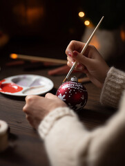 Artisan hands bring a red Christmas ornament to life with careful brush strokes in a warm setting Generative AI