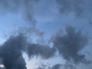 Dramatic sunset sky with dark storm clouds and a warm orange glow on the horizon, creating a powerful contrast between light and shadow in the evening atmosphere.