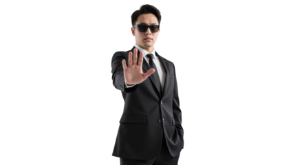 Confident man in black suit and sunglasses holds up his hand in stopping gesture, exuding authority and style