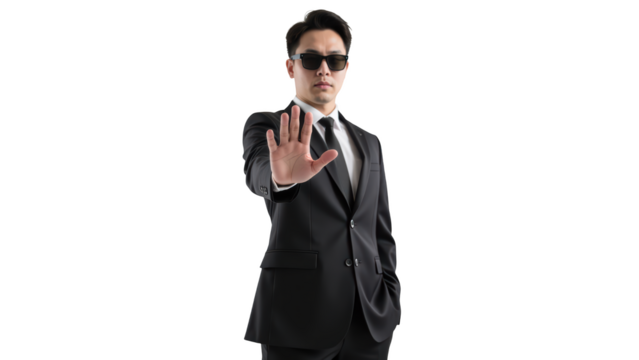 Confident man in black suit and sunglasses holds up his hand in stopping gesture, exuding authority and style
