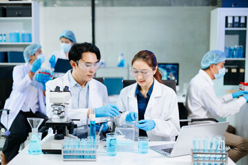Team of scientists analyzing blue liquid samples in a modern lab, showcasing biotechnology,...