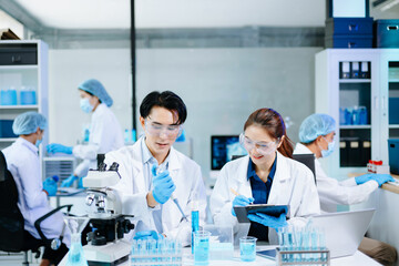 Scientists collaborating in a modern lab with microscopes and blue liquids, representing biotechnology, chemistry, and medical research innovation.