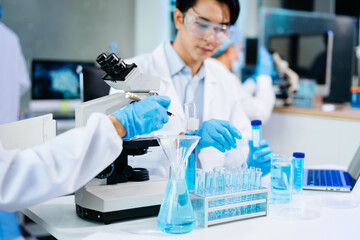 cientists working together in a modern lab with microscopes and blue liquids, symbolizing...