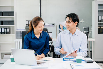 Obraz premium Young Asian professionals collaborating in modern office, discussing business strategy, teamwork, and success. Perfect for corporate, startup
