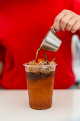 A shot of espresso poured into fresh tea in plastic glass