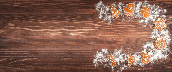 Festive Christmas background with decorated gingerbread cookies and powdered sugar on a rustic wooden table, perfect for holiday design and copy space