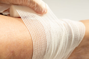 Nurse carefully bandaging woman ankle with medical wrap, applying bandage to injured leg, healthcare treatment for sprain or injury, first aid support, medical care and rehabilitation