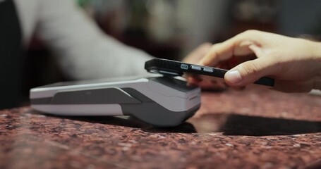 Purchase by smartphone on card reader. Pos-terminal in hand of waiter worker close-up. Modern technologies and restaurant business concept. - Powered by Adobe