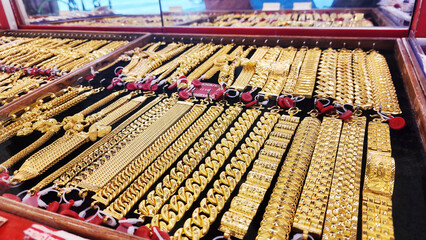 Gold jewelry, Rows of gold bracelet and necklaces displayed in jewelry store showcase, symbolizing...