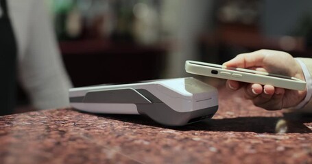 Purchase by smartphone on card reader. Pos-terminal in hand of waiter worker close-up. Modern technologies and restaurant business concept. - Powered by Adobe
