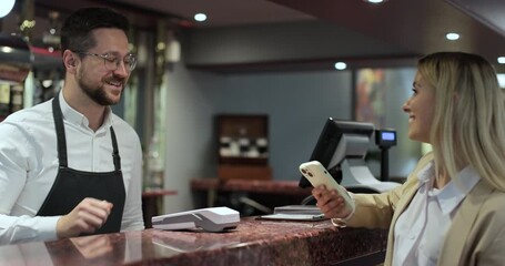 Woman holding smartphone with an NFC payment technology used for paying in a restaurant. Contactless mobile phone to credit card system in cafe with digital transaction service. - Powered by Adobe