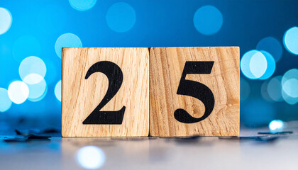 Wooden cubes with number 25 with confetti, blue bokeh light. Celebration mood.