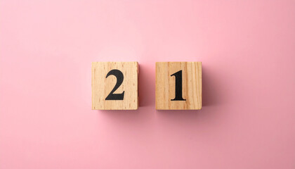 Wooden cubes with number 21 on smooth pink background, top view.