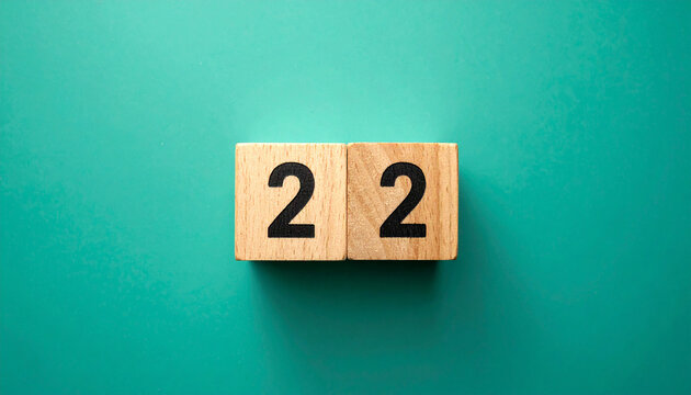Wooden cubes with number 22 on smooth teal green background, top view.