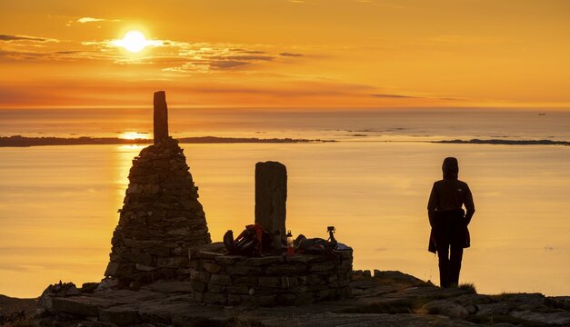 Silhouette of a woman watching the sunset next to cairns, Rørsethornet stone staircase, with 3292 steps one of the longest continuous stone staircases in the world, Sherpatreppe or Midsundtreppe or Midsundtrappene, Rørsethornet hike, Otroya or Otrøya island, Møre og Romsdal, Norway