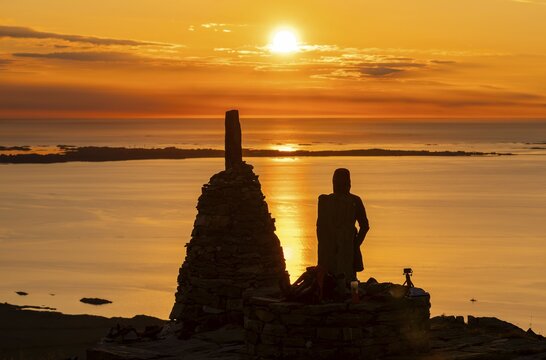 Silhouette of a woman watching the sunset next to cairns, Rørsethornet stone staircase, with 3292 steps one of the longest continuous stone staircases in the world, Sherpatreppe or Midsundtreppe or Midsundtrappene, Rørsethornet hike, Otroya or Otrøya island, Møre og Romsdal, Norway