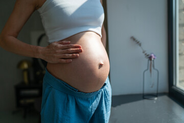 Pregnant woman gently touching her tummy, Woman waiting for baby in home