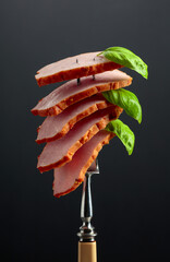 Smoked ham with basil on a fork.
