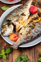 Baked dorado fish with plums served on a plate.
