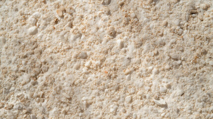 Close up of textured beige stone surface with small pebbles and rough texture. natural pattern creates earthy and organic feel