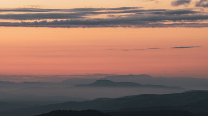Fototapeta premium Layers of mountain hills under golden and orange evening sky