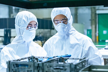 Male and female workers wearing protective clothing working in a factory