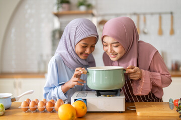 Muslim mother teaching daughter cooking halal food family lifestyle with pot wearing hijab with fresh fruit and vegetables at home kitchen, cooking lesson, islamic parenting education, muslim wellness
