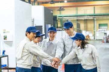 Fototapeta premium 工場の中で円陣を組む作業員グループ