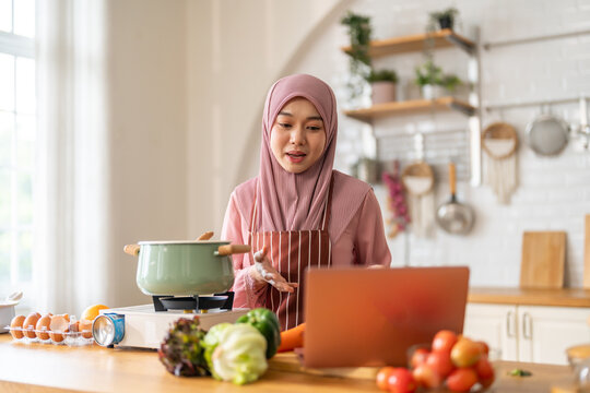 Muslim woman vlogger live streaming cooking online in kitchen look at camera with vegetables, content creator culinary class at home studio, halal food influencer cooking live, video for social media