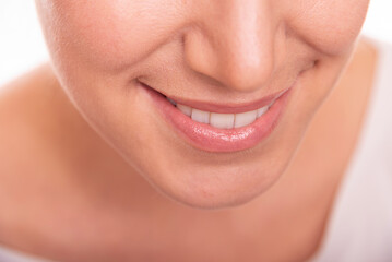Close-up image of a smiling woman showing her white teeth and natural lips, representing happiness, confidence, and dental health.