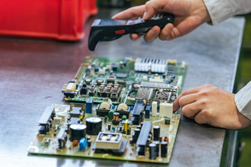 A worker inspects products using a handheld terminal at a factory