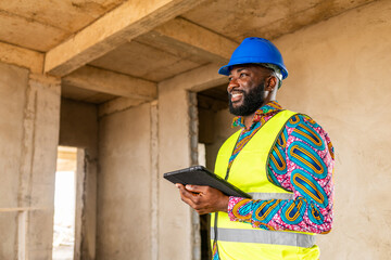 African construction engineer smiles confidently while holding smart tablet on-site
