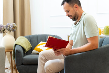 Man relaxing in armchair reading book at home