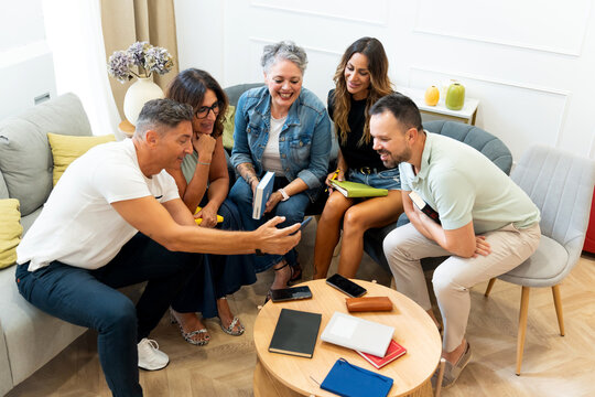 Friends sharing smartphone content during book club meeting