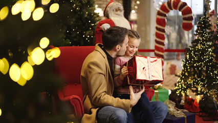 Father and daughter share a special moment opening a Christmas gift together
