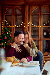Couple Celebrating Christmas Dinner At Home With Tree And Cozy Fairy Lights