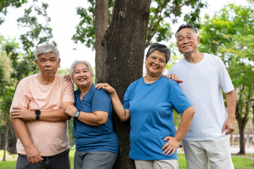 Four older adults enjoy a cheerful moment together in a lush outdoor setting. Their smiles and relaxed poses highlight themes of friendship, active aging, and joy of social connection in later life.