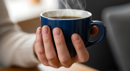 Hand holding a steaming cup of coffee