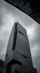 Modern skyscraper with dark glass facade against cloudy sky.