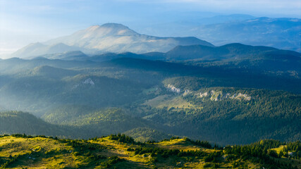 Fototapeta premium Layers of mountains and forest valleys softly lit by early morning sun