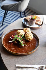 Traditional Czech venison goulash with bread dumplings, autumn seasonal dish served in a restaurant, rustic comfort food.