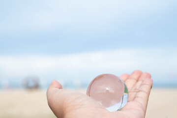 Hand holding a transparent glass globe symbolizes global care, environmental responsibility, and sustainability, promoting the idea of protecting our planet for future generations.