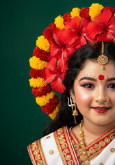 Bal Durga child goddess portrait in white and red attire with floral halo of hibiscus and marigolds, trident earring, red bindi, and emerald green background