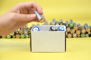 Used AA batteries and proper disposal of environmentally and soil toxic batteries on a green background.
