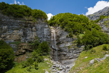 This landscape photo was taken in Europe, France, Auvergne-Rhone-Alpes, Haute-Savoie, Sixt-Fer-a-Cheval, in summer. It shows the waterfall on a cliff in the Cirque du Fer-a-Cheval, under the Sun.