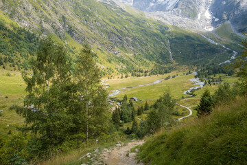 This landscape photo was taken in Europe, France, Auvergne Rhone Alpes, Haute Savoie, in summer. It shows the hiking trail to the chalets du Miage, under the sun.