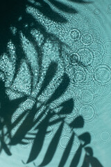 Blue water texture background on the noon sunlight with tropical leaves shadow.